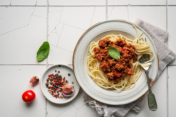Wall Mural - Pasta spaghetti bolognese with minced beef sauce, tomatoes, parmesan cheese and fresh basil in a plate on white tile background. Italian food, top view