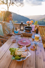 Wall Mural - dinner in the mountains of Chiang Mai Thailand, table bbq, kitchen tongs grilling beef and bacon on the grill plate. Eating Korean Barbecue buffet in the restaurant. woman Korean barbecue