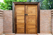 Wooden Door And Wood Frame With The Bronze Knocked Chinese Lion Head Style On It. This Is Middle Of The Brick Wall In The Garden Environment