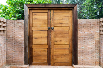 Wooden door and wood frame with the Bronze Knocked Chinese Lion head style on it. This is middle of the brick wall in the garden environment