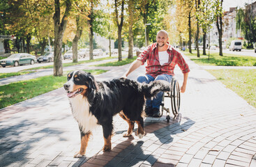 Wall Mural - Happy young man with a physical disability who uses wheelchair with his dog.