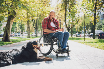 Wall Mural - Happy young man with a physical disability who uses wheelchair with his dog.