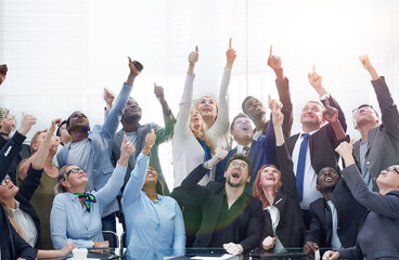 Businessmen pointing upwards while sitting at table during meeting