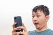 An Asian man is surprised when he looks at his smartphone.