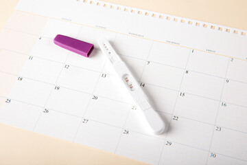 A positive pregnancy test kit is placed on the calendar