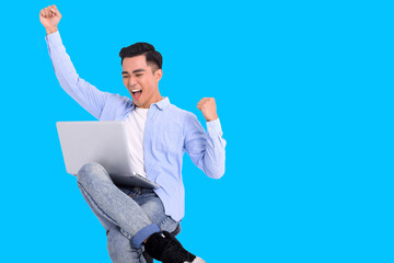 Excited young man dressed casual  and working with laptop