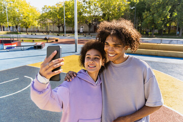 Wall Mural - Interracial young couple dating outdoors, colored and modern urban background