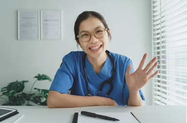 Smiling Asian Female Doctor looking at webcam making conference video call