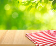 © hakinmhan - Checked,tablecloth on wood with blur green garden background.Summer and picnic concepts.Design for key visual food and drink