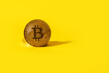 golden bitcoin over yellow background, cryptocurrency concept