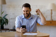 © fizkes - Happy excited smartphone user enjoying win, success, achieve, high job result. Euphoric businessman using cellphone, reading text message, feeling joy, making hand winner gesture, laughing