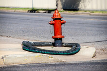 Red Fire Hydrant With Fire Hose Wrapped Around It On Corner Of Street With Curb.j