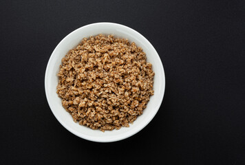 Wall Mural - Bowl of buckwheat flakes on black background
