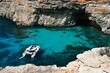 Comino island with cliffs, tourist boats and blue sea.
