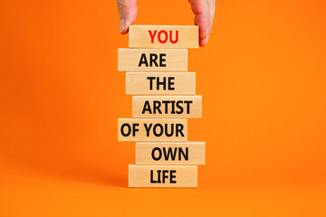 Wall Mural - You artist of your life symbol. Wooden blocks with words You are the artist of your own life. Beautiful orange background, copy space. Businessman hand. Business, motivational lifestyle concept.
