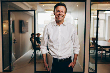 Smiling businessman carrying a laptop at work