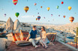 © travnikovstudio - Happy young couple during sunrise watching hot air balloons in Cappadocia, Turkey