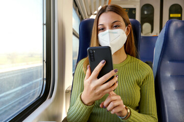 Wall Mural - Train passenger using smartphone app during travel commute wearing protective face mask