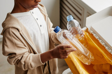 Wall Mural - Cropped shot of African-American boy putting plastic in recycling bins at home, copy space