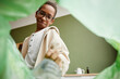 © Seventyfour - Low angle view at African-American boy sorting household waste at home, recycling bin POV