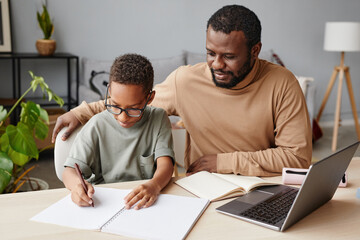 Canvas Print - Portrait of African-American father helping son with homeschooling while studying at home, copy space