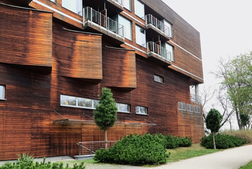 A beautiful wooden apartment building with a well-groomed territory near in summer time against a sky.The concept of rent and buying real estate