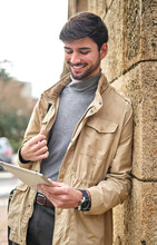 Man Using Tablet While Leaning On Stone Column