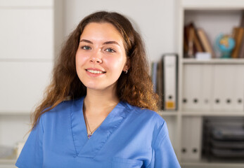 Wall Mural - Portrait of european doctor female in blue shirt standing in white medical office in clinic