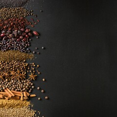 Spices and herbs on background of black table with empty space.