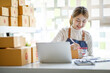 © David - Startup SME small business entrepreneur SME or freelance Asian woman using a laptop with box, Young success Asian woman with her hand lift up, online marketing packaging box and delivery, SME concept.