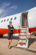 © Kostiantyn - Woman stewardess standing near airplane and inviting on board