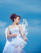 Valentin Teenager Girl With Bow Arrow Ready To Shoot. Cute Angel Teen With Feathers Wings On Sky. Valentines Day.