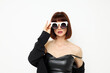 © Tatiana - attractive woman posing with sunglasses a leather suit black jacket light background