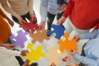 © Studio Romantic - Close up top view of diverse multiracial businesspeople hold jigsaw pieces connect puzzle seek for business solution in office. Employees or colleagues involved in teambuilding activity or training.