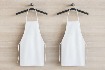 Poster - Empty white kitchen aprons on hangers. Light wood background. Chef and cooking concept. Mock up place. 3D Rendering.