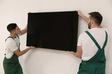 Wall Mural - Professional technicians installing modern flat screen TV on wall indoors