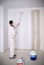 House Painter Painting Wall With Roller At Construction Site