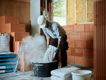 Bricklayer Putting Cement In Tub At Construction Site