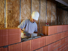 Bricklayer Applying Cement On Bricks With Hand Tool At Construction Site