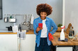 © Westend61 - Smiling young Afro woman text messaging on smart phone by spray bottle at kitchen counter