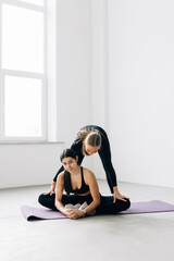 Wall Mural - Fitness woman training with her personal trainer at gym. Young two women doing stretching exercises, copy space