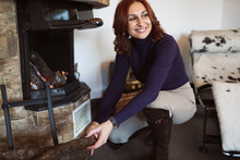 Smiling Woman Kneeling By Fireplace In Living Room