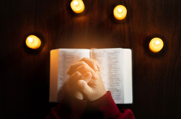 Wall Mural - Christian hand while praying and worship for christian religion with blurred of her body background, Casual man praying with her hands together over a closed Bible. christian background. freedom.