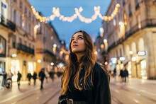 Beautiful Young Woman Looking Up On City Street At Night