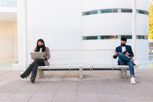 Business Colleagues Following Social Distancing Sitting On Bench