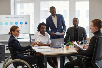 High angle view at businesswoman in wheelchair leading business meeting with diverse group of people