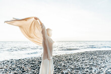 Woman Holding Blanket Aloft At Beach