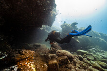 Young Man With Diving Equipment By Rocks Undersea
