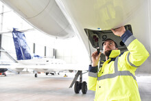 Airport Workers Check An Aircraft For Safety In A Hangar