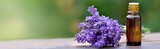 Fototapeta  - bottle of essential oil and bouquet of  lavender flower arranged on a wooden table on green background